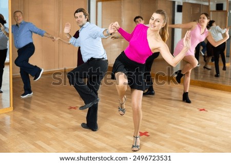 Active middle-aged pair practicing Latino dance in training hall during dancing-classes. Pairs training ballroom dance