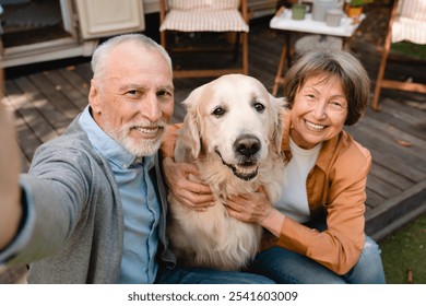 Active modern senior old couple spouses taking selfie vlogging blogging with dog golden retriever on social media traveling by motor home camper van trailer - Powered by Shutterstock