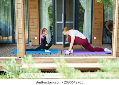 Active mother and daughter doing sport on wooden porch - Powered by Shutterstock