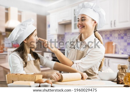 Active mother involves small kid girl cooking cookie dough