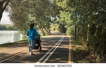 Active mother jogging. Jogging or power walking woman with a baby stroller in morning. Mother with child in stroller running