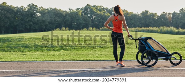 Active mother in sportswear uses jogging\
stroller for running at park. Happy woman having fun while workout\
outdoor. Jogging stroller\
advertisement