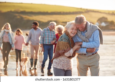 Active Multi-Generation Family With Dog Walking Along Shore On Winter Beach Vacation