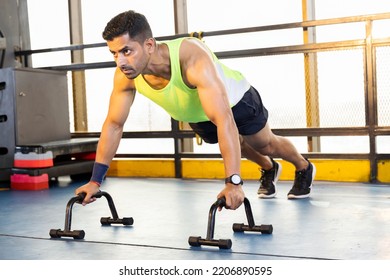 Active muscular man in sportswear doing push ups with bars at gym - Powered by Shutterstock