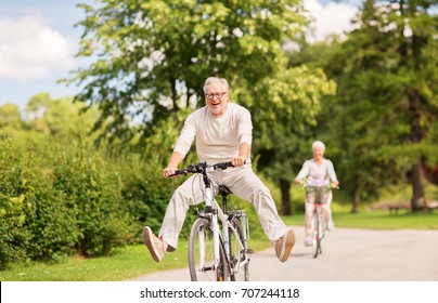 concepto de edad avanzada activa, personas y estilo de vida - feliz pareja de edad avanzada en bicicleta en el parque de verano