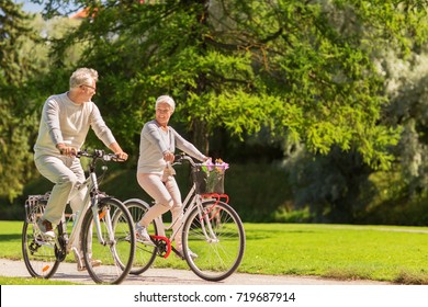 active old age, people and lifestyle concept - happy senior couple riding bicycles at summer park