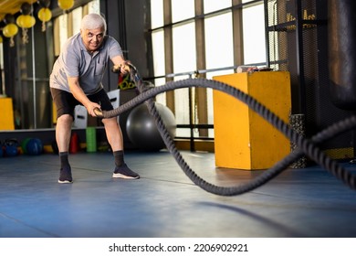  Active old man in sportswear training with battle rope in cross fit gym - Powered by Shutterstock