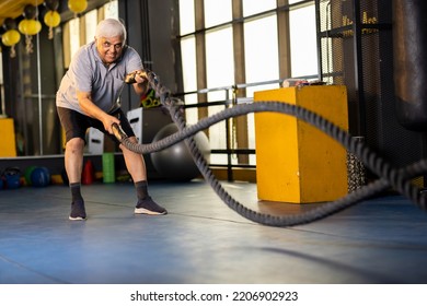  Active old man in sportswear training with battle rope in cross fit gym - Powered by Shutterstock