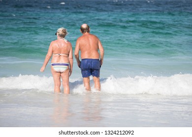 Active Older Couple, Seniors Healthy And Fit In The Surf At The Beach On A Summer Day. Love And Companionship