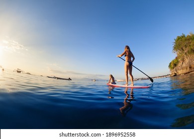 Active paddle boarder at sunset sea. Young mother with little clild paddling on stand up paddleboard. Healthy lifestyle. Water sport, SUP surfing tour in adventure camp on family summer beach vacation - Powered by Shutterstock