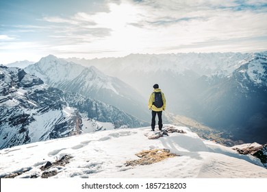 Active people in nature concept. Dressed bright yellow jacket male backpacker enjoying the view as she have mountain walk.Tourist with a backpack and mountain panorama. Adventure concept