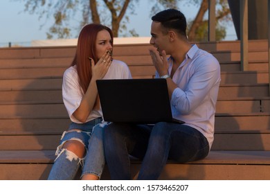 Active People. Photo Of Group Of Young Serious Bussines Couple Holding Laptop Computer Outside. Two Bussines People Using Laptop Outside Discussing Ideas With Colleagues.