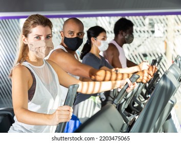 Active People In Protective Masks Having Running Elliptical Trainer Class In Health Club