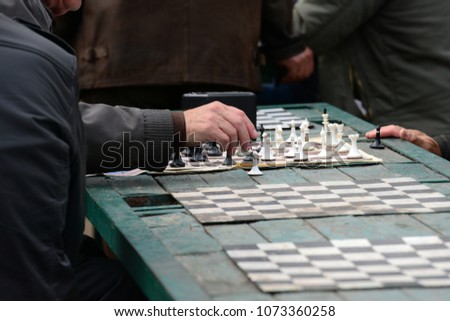 Active people in their free time on vacation with pleasure playing chess on the street. Figures and chess board close-up.
