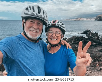 Active positive couple of seniors biking with bicycles at sea taking a memory photo embracing looking at camera enjoying healthy lifestyle in retirement. Horizon over water - Powered by Shutterstock