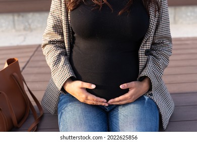 Active Pregnancy Concept. Close-up Of Belly Of Happy Young Business Or Student Pregnant Woman Sitting On The Bench. Future Mom Working Or Studying On Her Late Pregnancy Period.