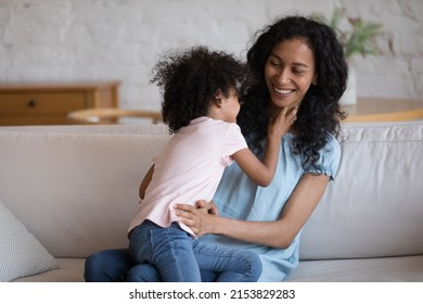 Active preschool African kid tickling happy cheerful mom. Black mother and daughter girl playing on couch at home, hugging, cuddling, tickling, laughing, having fun. Childcare, motherhood concept