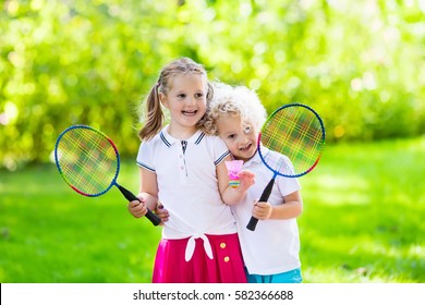 Active preschool girl and boy playing badminton in outdoor court in summer. Kids play tennis. School sports for children. Racquet and shuttlecock sport for child athlete. Kid with racket and shuttle
