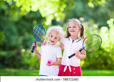 Active preschool girl and boy playing badminton in outdoor court in summer. Kids play tennis. School sports for children. Racquet and shuttlecock sport for child athlete. Kid with racket and shuttle.