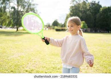 Active preschool girl playing badminton in outdoor court in summer. Kid with racket.