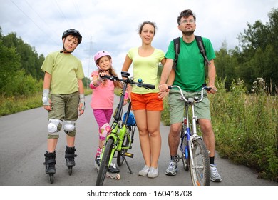 Active rest on nature of the family of four with roller skates and a bicycles