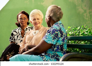 Active Retired Elderly Women And Free Time, Group Of Happy Senior African American And Caucasian Female Friends Talking And Sitting On Bench In Park