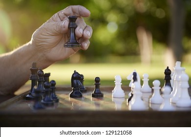 Active retired persons, hand of old man holding chess piece in park. Closeup shot, copy space - Powered by Shutterstock