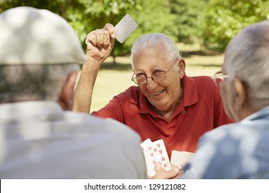 Active Retirement, Old People And Seniors Free Time, Group Of Three Elderly Men Having Fun And Playing Cards Game At Park