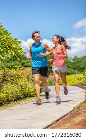 Active Runners Couple Running Talking Happy Training Buddy Outside Workout Outdoors In Summer Park. Woman And Man Jogging Healthy Cardio Workout Lifestyle.