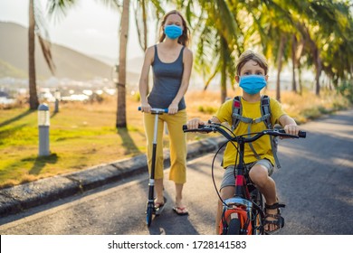 Active School Kid Boy And His Mom In Medical Mask Riding A Bike With Backpack On Sunny Day. Happy Child Biking On Way To School. You Need To Go To School In A Mask Because Of The Coronavirus Epidemic