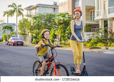 Active School Kid Boy And His Mom In Safety Helmet Riding A Bike With Backpack On Sunny Day. Happy Child Biking On Way To School. Safe Way For Kids Outdoors To School