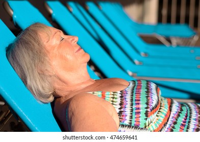 Active Senior Blond Woman Sunbathing On A Recliner Chair With Closed Eyes