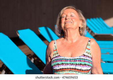 Active Senior Blond Woman Sunbathing On A Recliner Chair With Closed Eyes