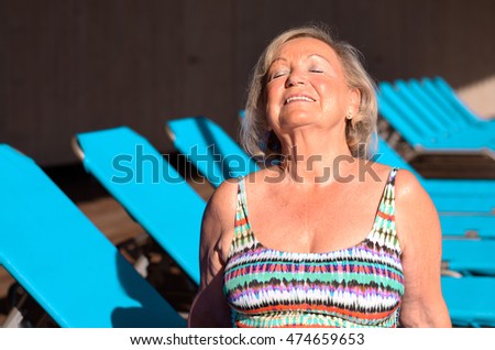 Active senior blond woman sunbathing on a recliner chair with closed Eyes