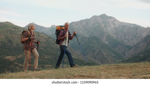 Active senior caucasian couple hiking in mountains with backpacks, enjoying their adventure 4k - Powered by Shutterstock
