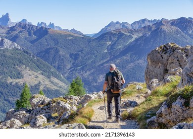 Active senior caucasian man hiking in Dolomiti mountains with backpack, enjoying his adventure. Carezza, Dolomites Alps, South Tyrol, Italy, Europe.