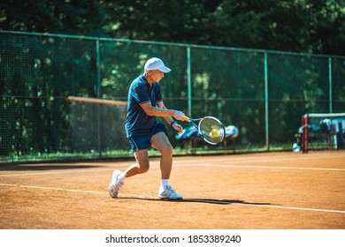 Active senior Caucasian man in sportswear playing tennis, hits a ball