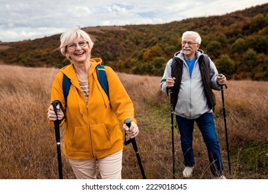 Active senior couple with backpacks hiking together in nature on autumn day. - Powered by Shutterstock