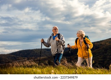 Active senior couple with backpacks hiking together in nature on autumn day. - Powered by Shutterstock