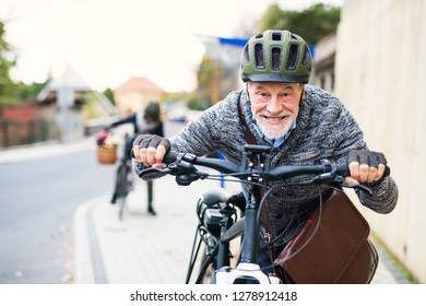 Active senior couple with electrobikes standing outdoors on a road in town. - Powered by Shutterstock