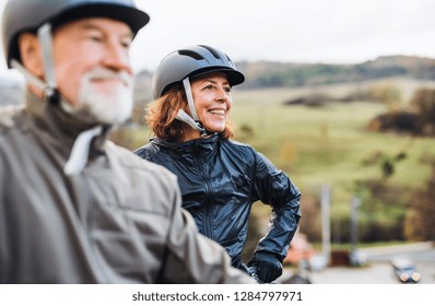 Active Senior Couple With Electrobikes Standing Outdoors On A Road In Nature.