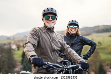 Active senior couple with electrobikes standing outdoors on a road in nature. - Powered by Shutterstock