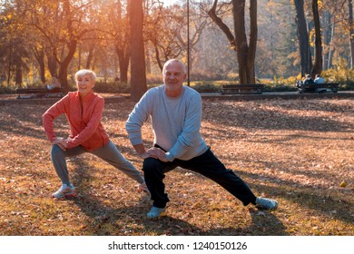 Active Senior Couple Exercising Outside In Autumn Park