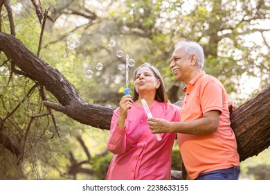 Active senior couple having fun blowing bubbles at park. - Powered by Shutterstock