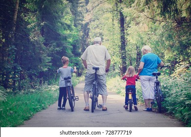 Active Senior Couple With Kids Riding Bikes In Nature