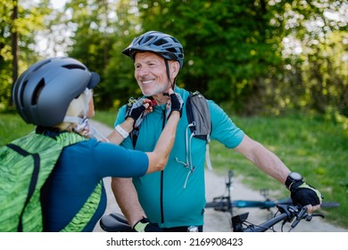 Active senior couple riding bicycles at summer park, putting on helmet, healthy lifestyle concept. - Shutterstock ID 2169908423