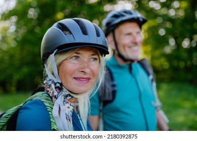 Active senior couple riding bicycles at summer park, woman with bicycle helmet, healthy lifestyle concept. - Shutterstock ID 2180392875