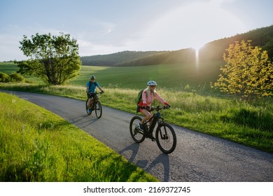 Active senior couple riding electric bicycles on road at summer park, healthy lifestyle concept. - Powered by Shutterstock