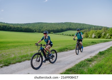 Active senior couple riding electric bicycles on trail at summer park, healthy lifestyle concept. - Powered by Shutterstock