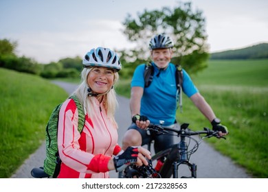 Active senior couple riding electric bicycles on road at summer park, healthy lifestyle concept. - Shutterstock ID 2172328563